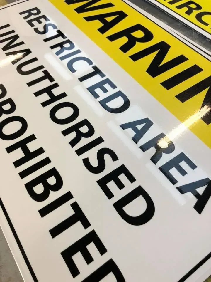 A yellow and white sign that says warning restricted area unauthorized