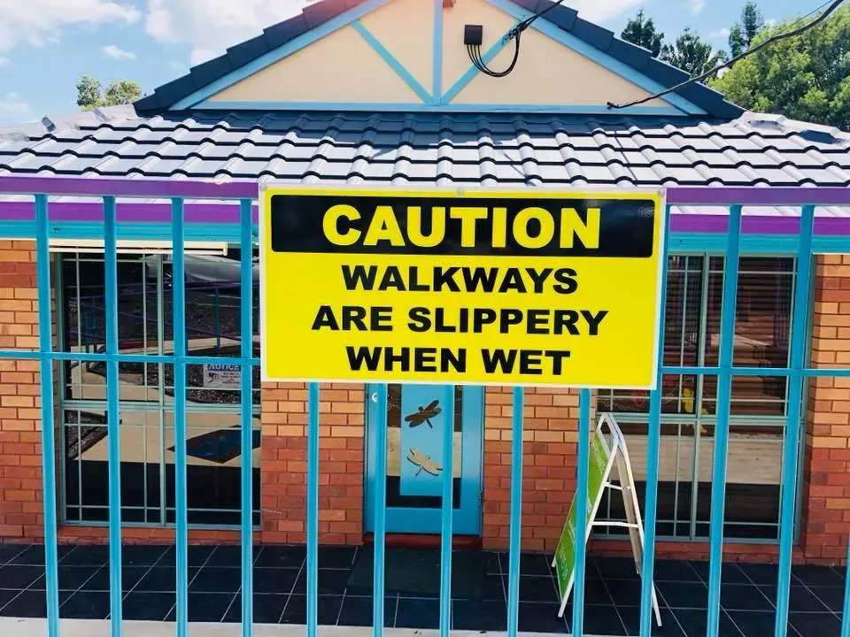 A yellow sign warns that walkways are slippery when wet