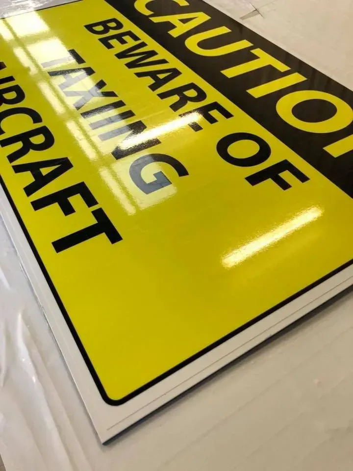 A yellow sign that says caution beware of taxing aircraft