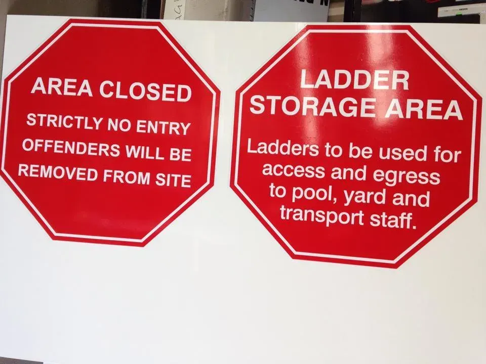 Two red signs that say area closed and ladder storage area