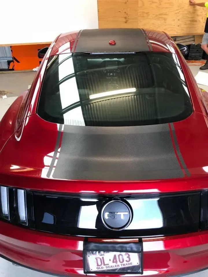 A red ford mustang with a license plate that says dl 403 is parked in a garage.