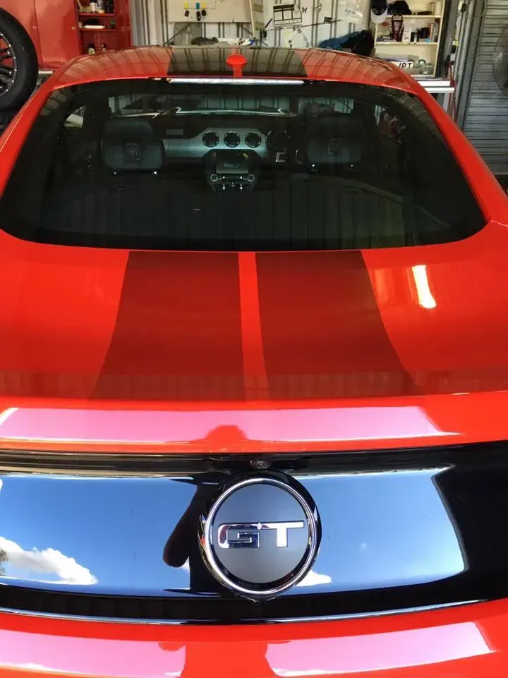 A red ford mustang is parked in a garage