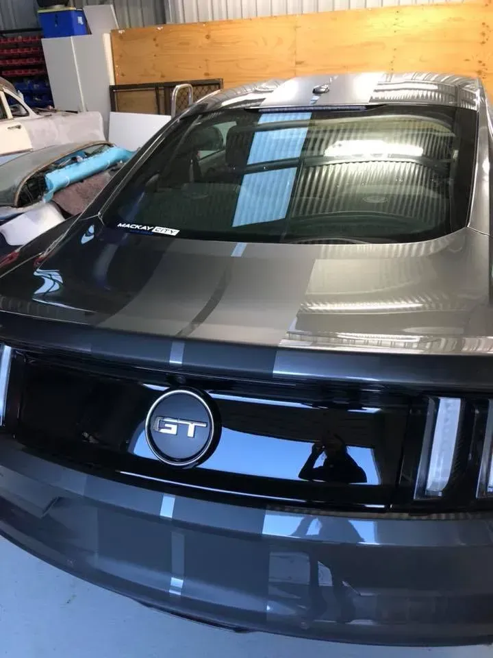 A black ford mustang is parked in a garage.