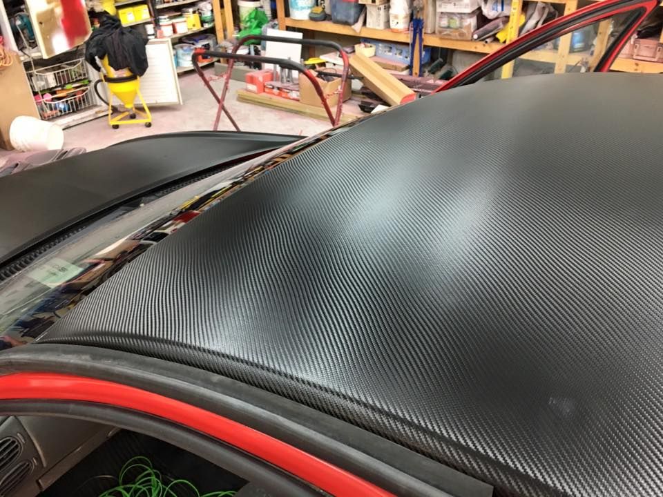 A black car with a red trim is sitting in a garage.