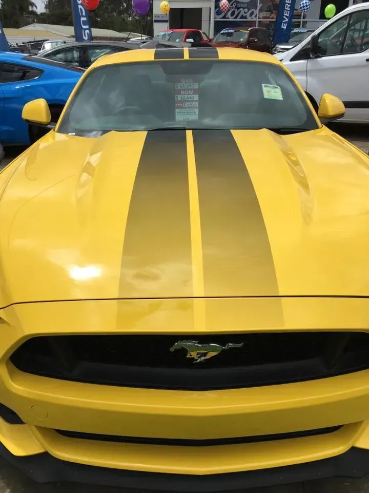 A yellow mustang with black stripes on the hood