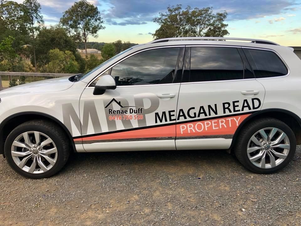 A white suv with a sticker on the side that says meagan read property.