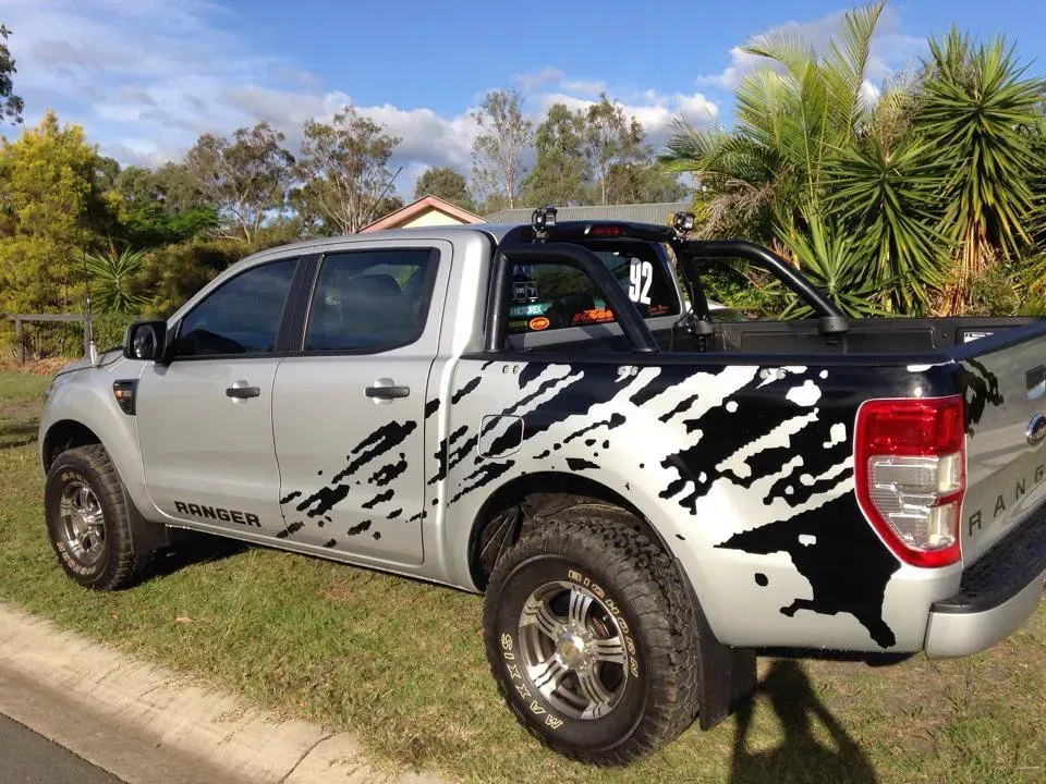 A silver truck with a black and white design on the side is parked on the side of the road.