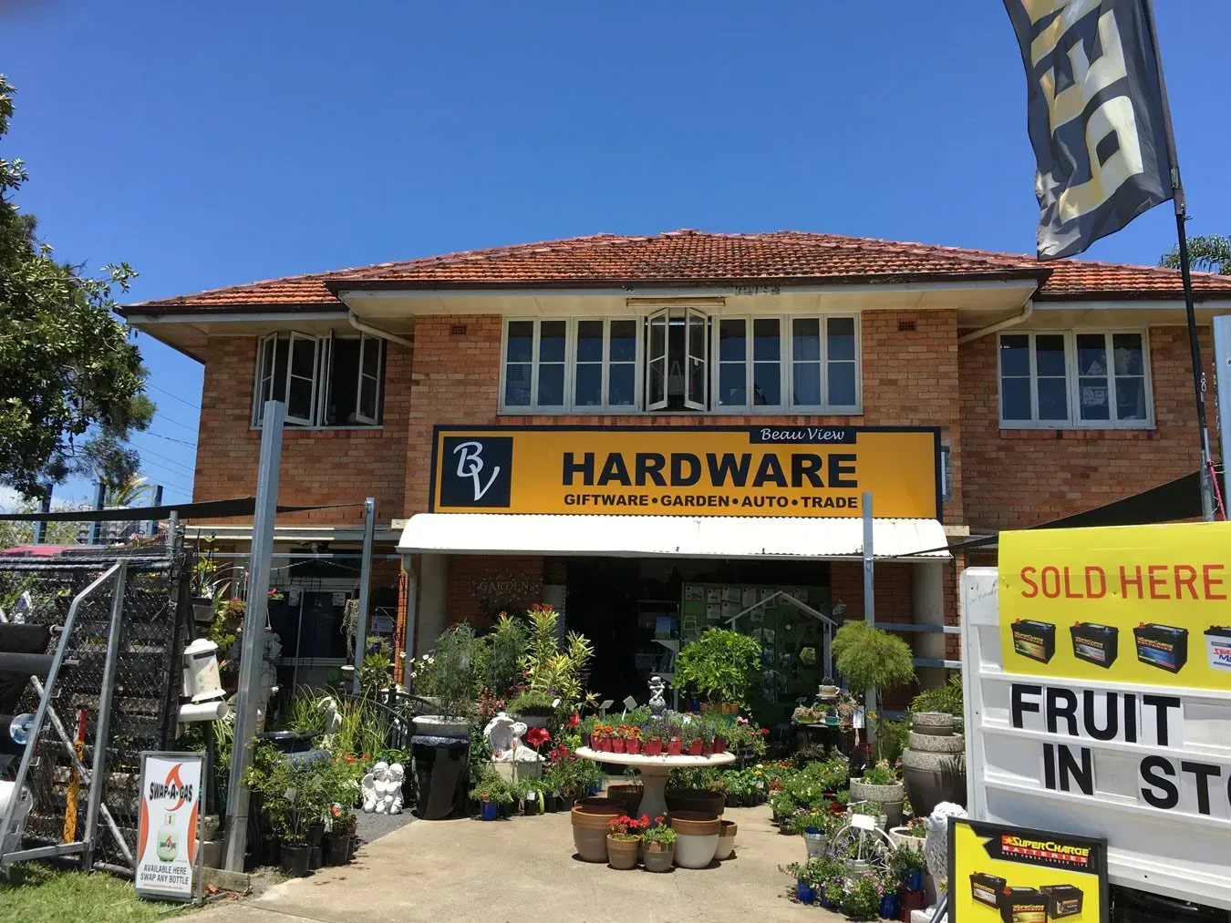 A hardware store with lots of plants in front of it.