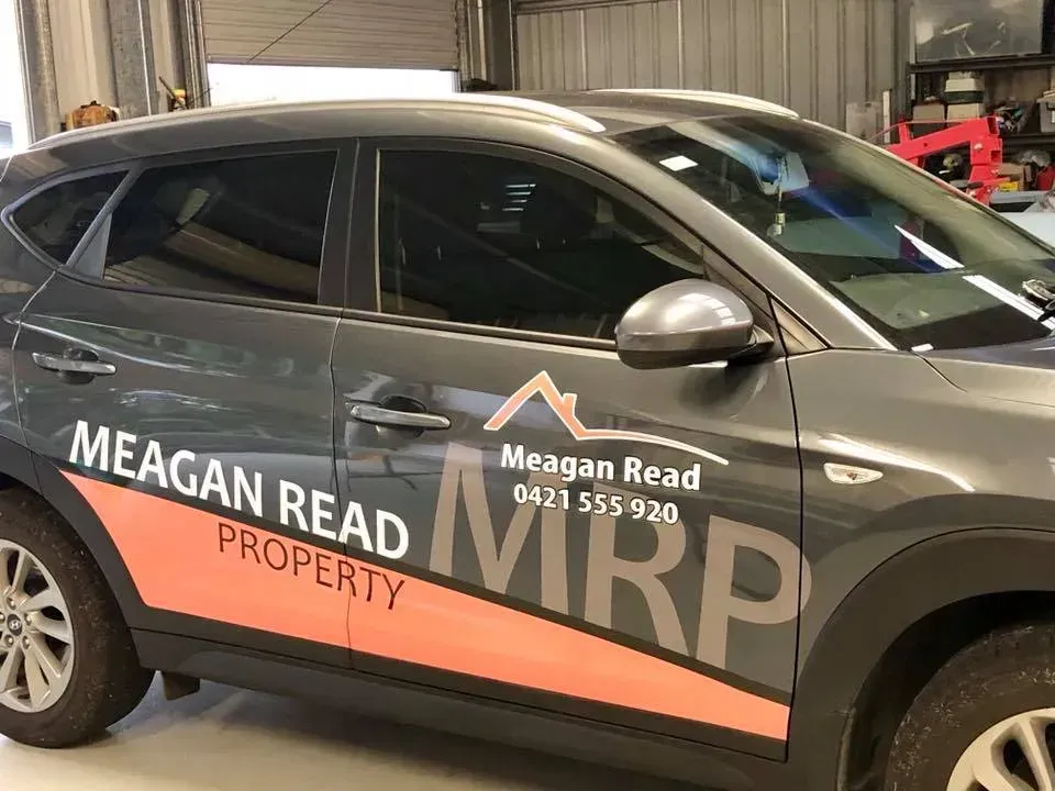 A car with a sticker on the side that says meagan read property.
