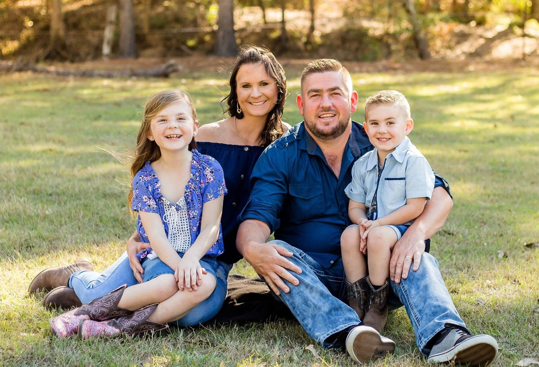 A family is posing for a picture while sitting on the grass.