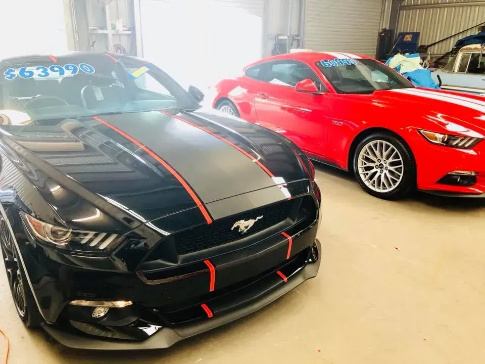 Two mustangs are parked next to each other in a garage.