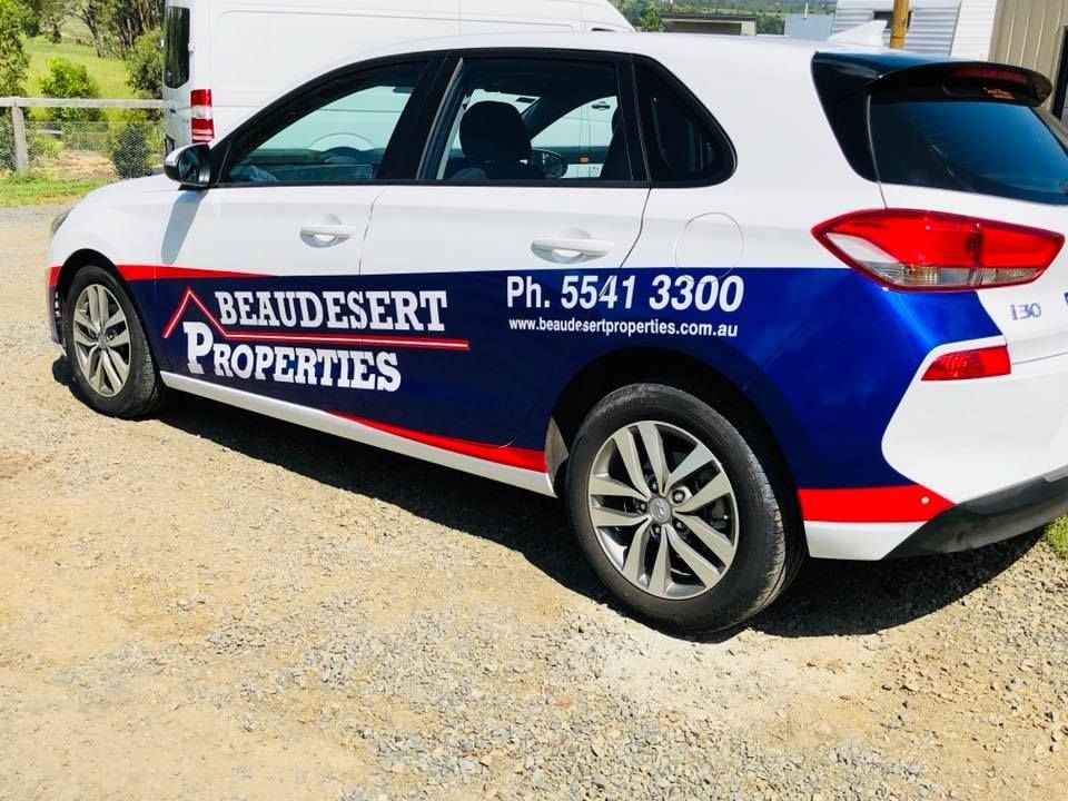 A blue and white car with beau desert properties written on the side