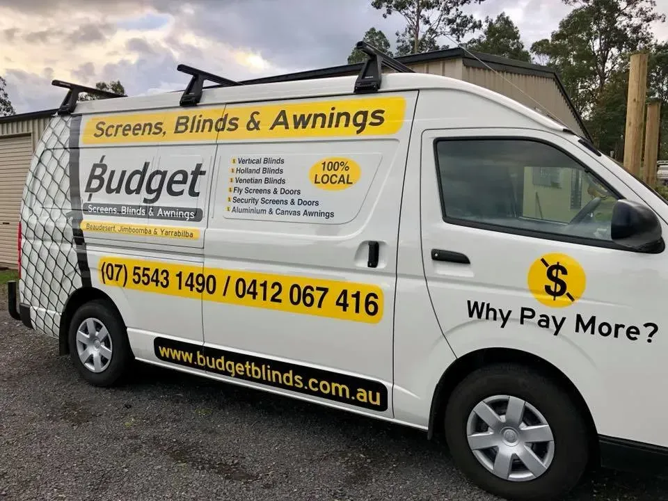 A white van that says budget screens blinds and awnings is parked on the side of the road.