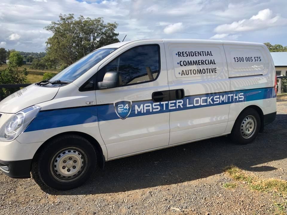 A white van with master locksmiths written on it is parked on a gravel road.