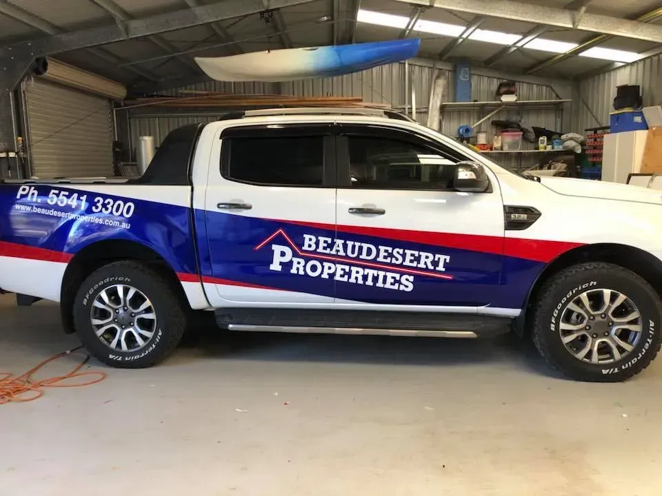 A white and blue truck is parked in a garage.