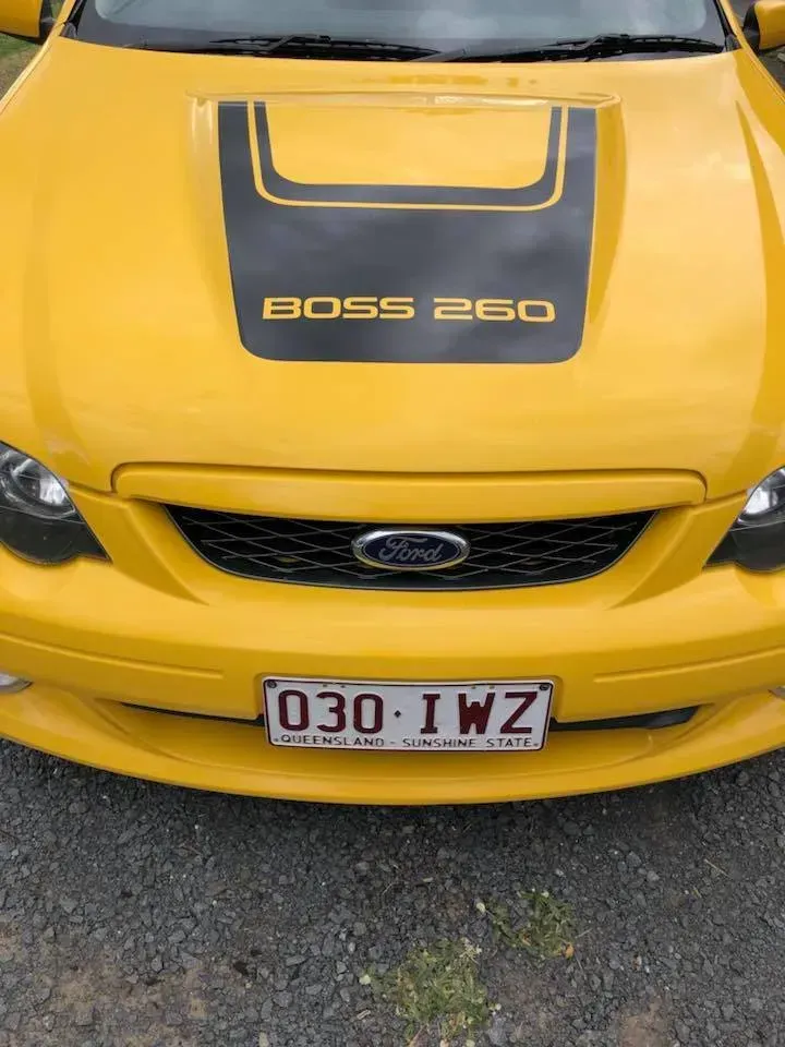 A yellow ford boss 260 is parked on a gravel road.