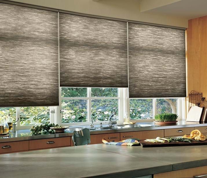 Kitchen with three closed, pleated blinds above a window, countertops, and a cutting board.