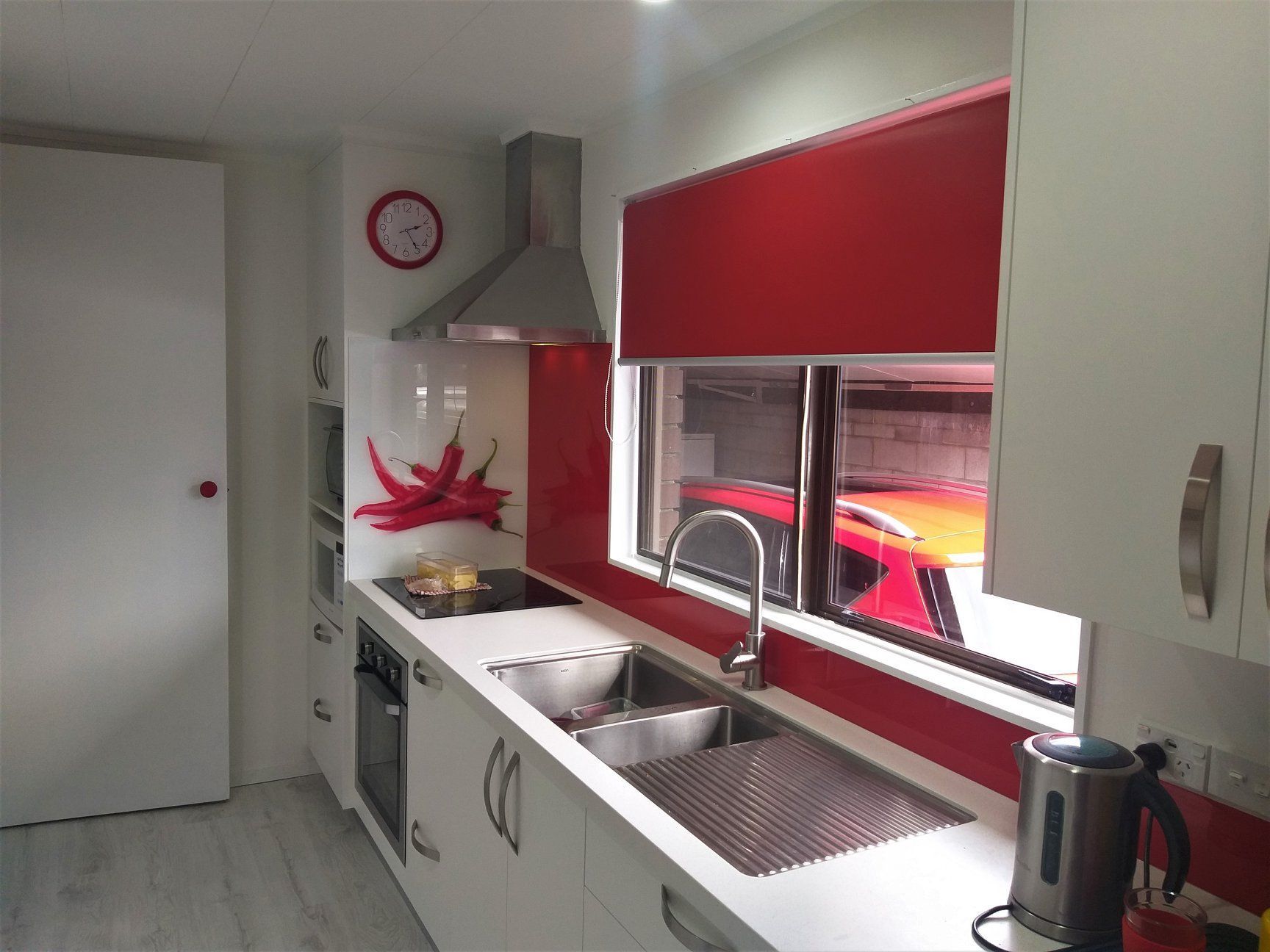 Modern kitchen with white cabinets, stainless steel appliances, and red accents.