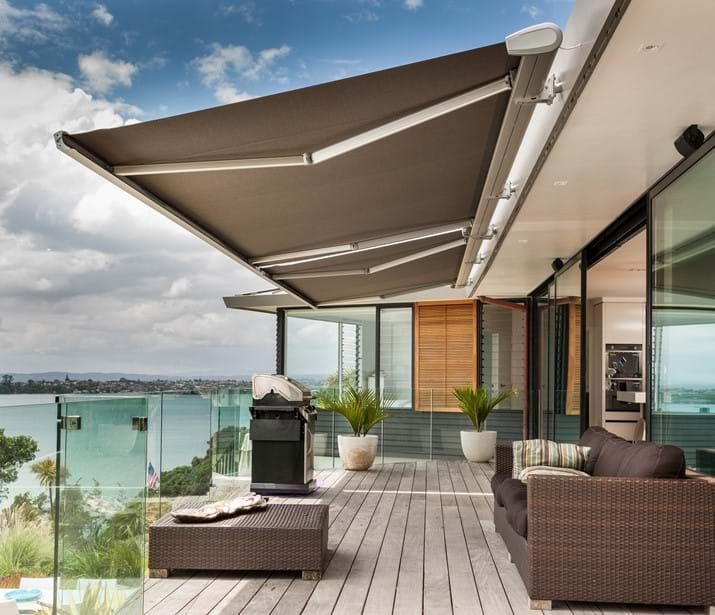 Patio with retractable awning, grill, furniture, and scenic view.