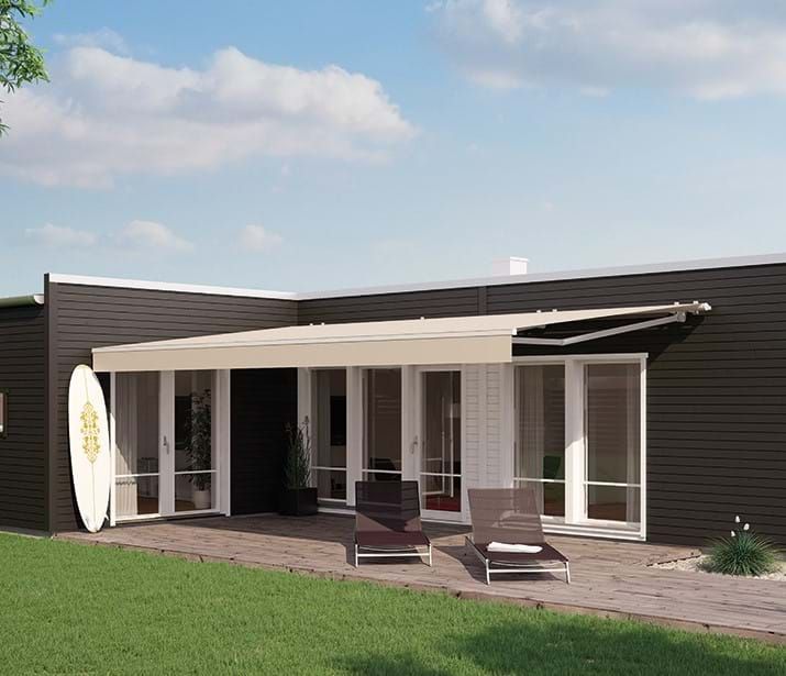 Dark modern house with covered patio, lounge chairs, and a surfboard. Dark modern house with covered patio, lounge chairs, and a surfboard.