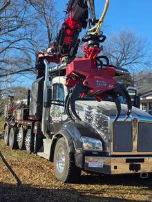 Red tow truck with a mounted crane parked outdoors on a sunny day.