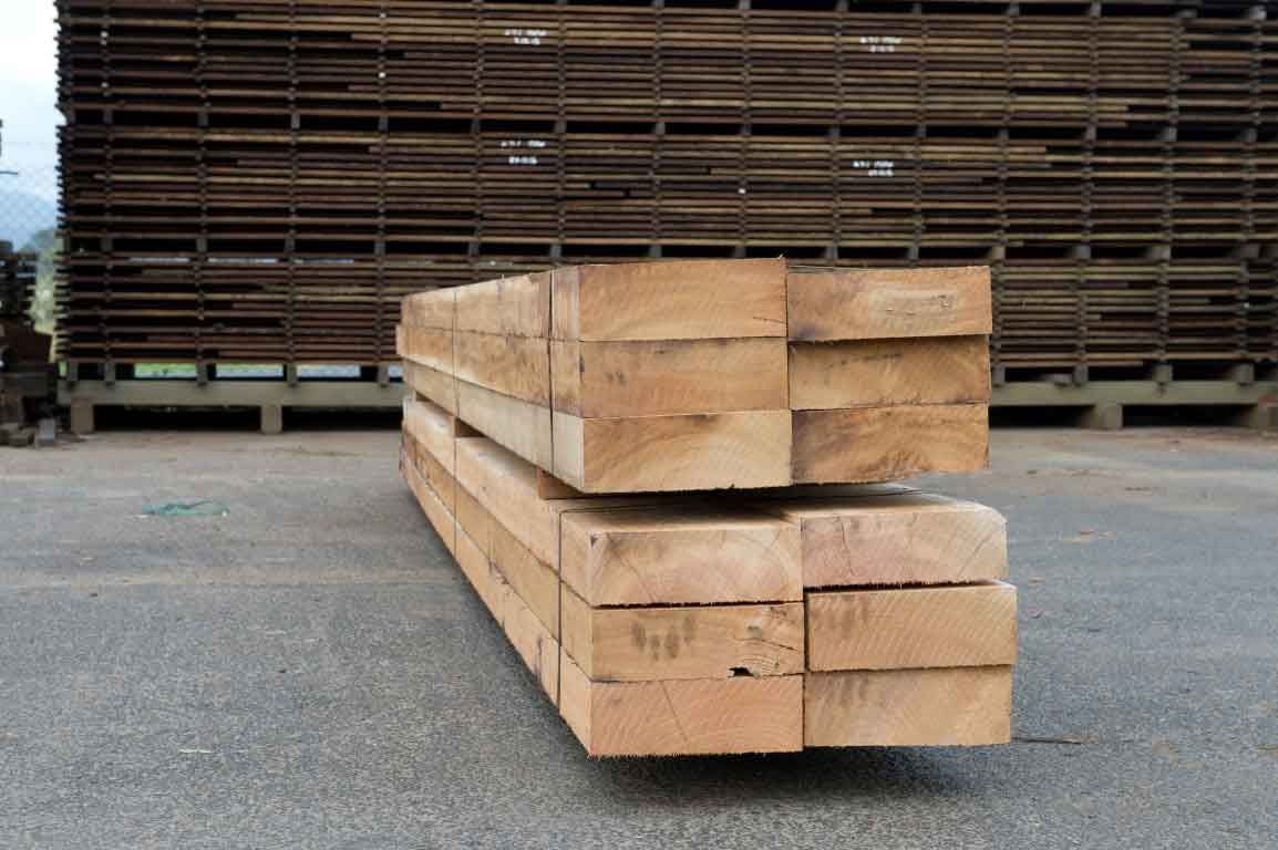 A Stack Of Wooden Boards Is Sitting On The Ground In Front Of A Warehouse – Beaudesert, QLD - Enrights Sawmill