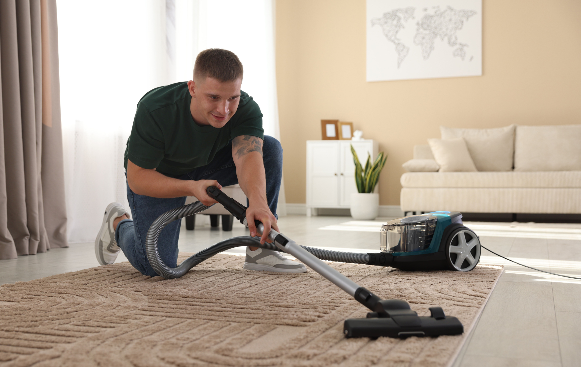 A person kneels on a living room rug, using a vacuum cleaner to clean the surface.