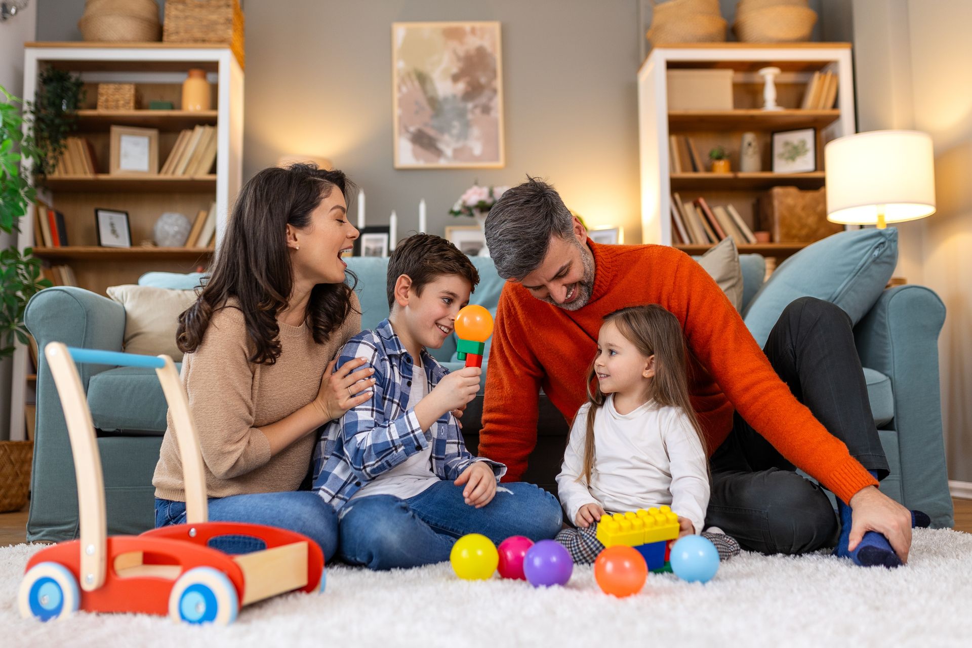 A family is sitting on the floor in a living room playing with toys.