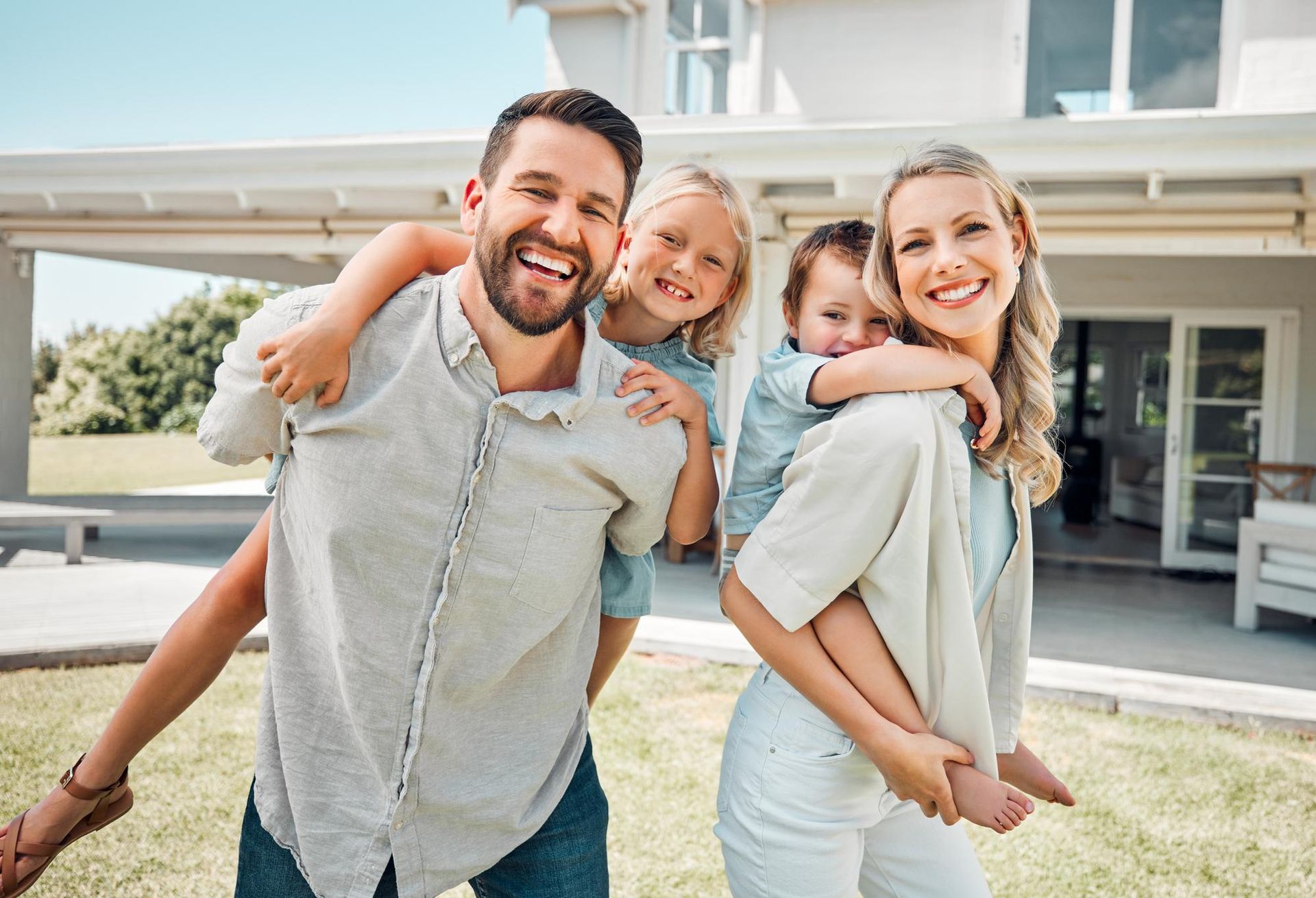 A family is posing for a picture in front of their new home.