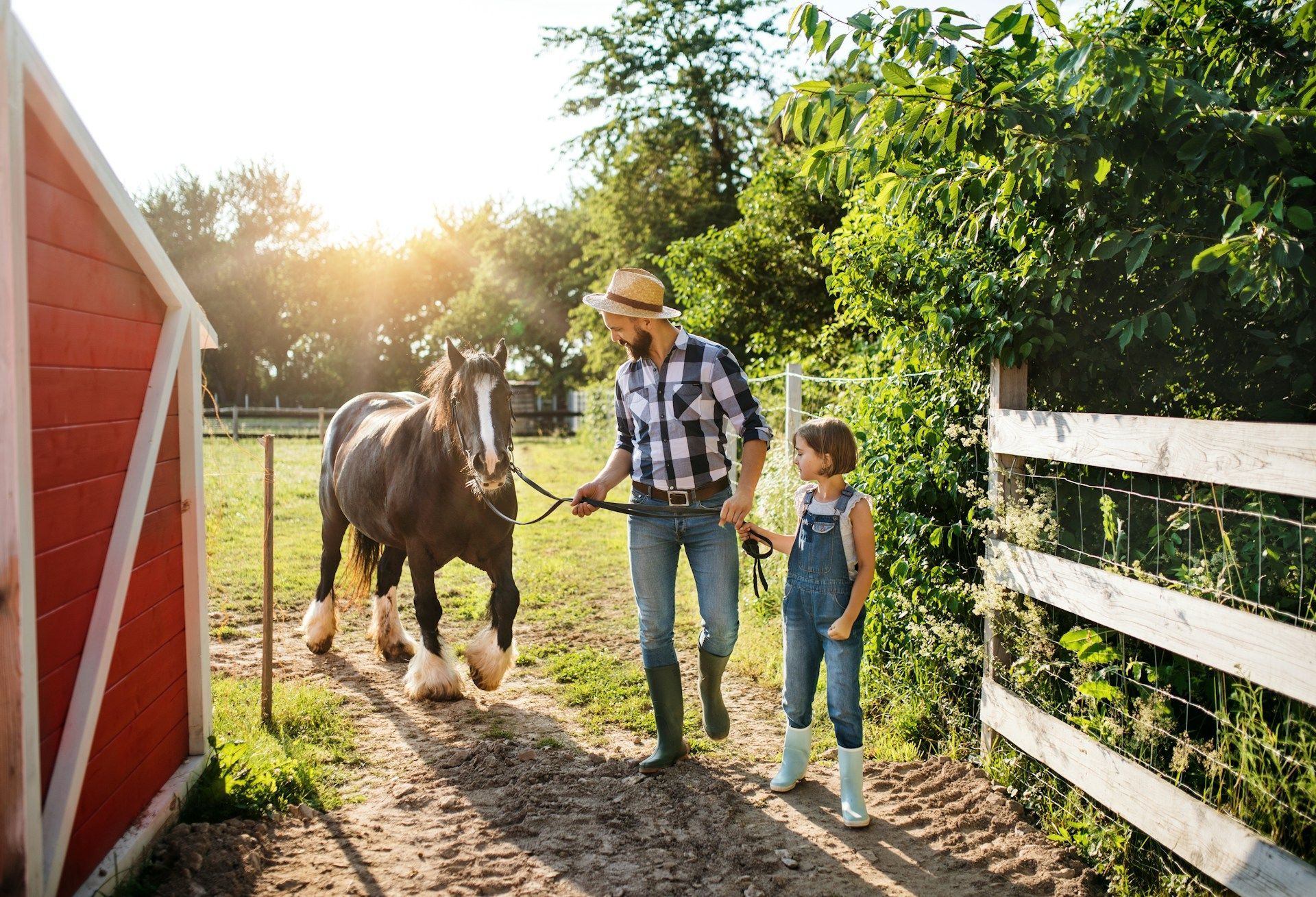 A man and a little girl are walking a horse in a field.