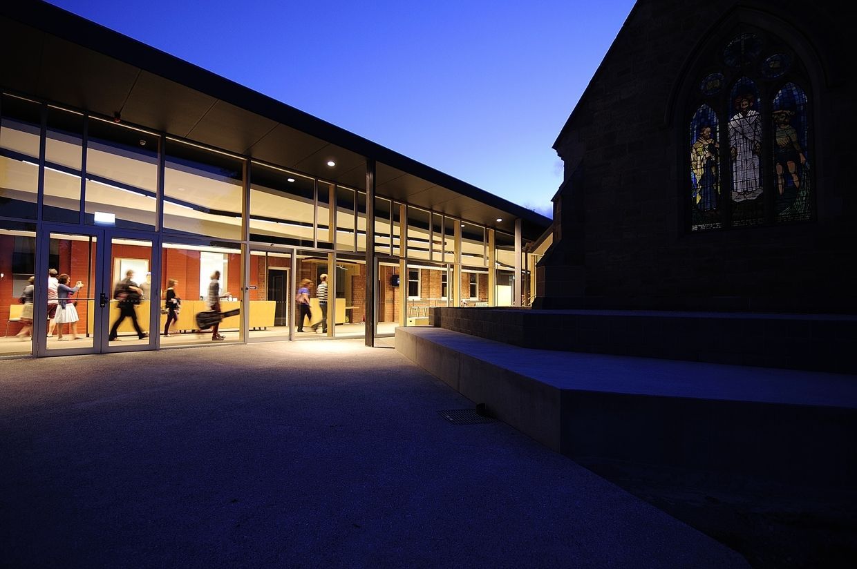 A Group Of People Are Walking In Front Of A Building At Night – Cambridge, TAS - Bennett Construction (TAS)