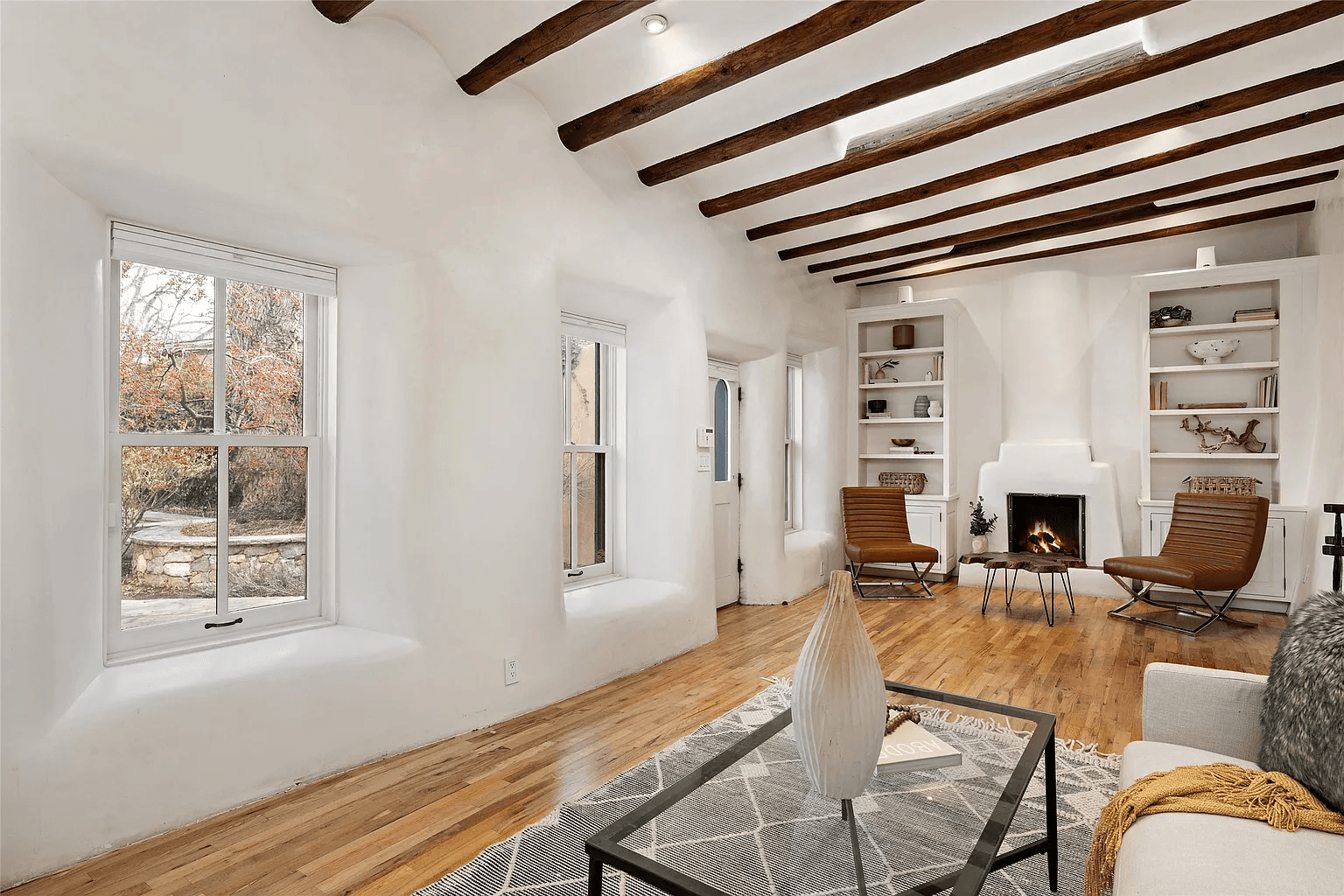 A living room with a fireplace , couch , chairs and a window.