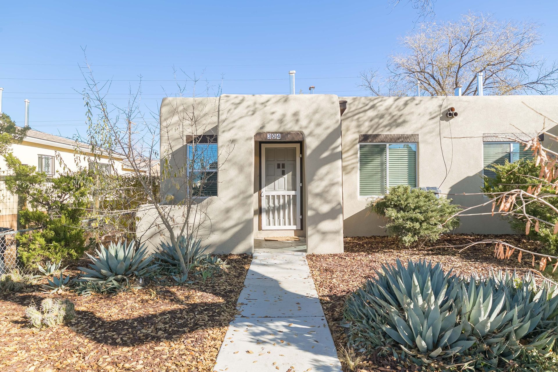 A small house with a concrete walkway leading to the front door.