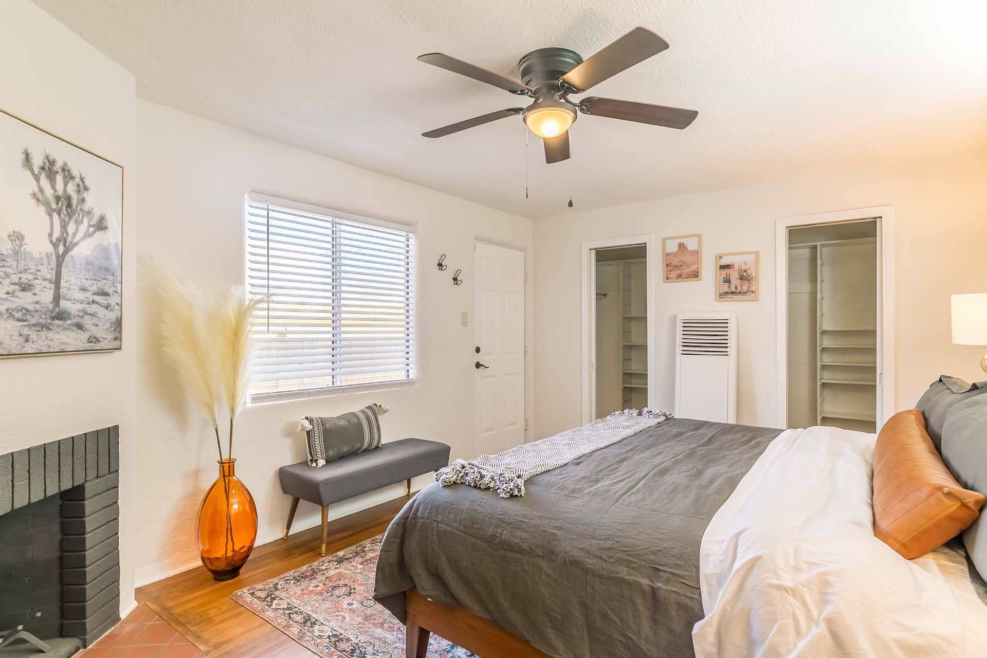 A bedroom with a bed , fireplace and ceiling fan.