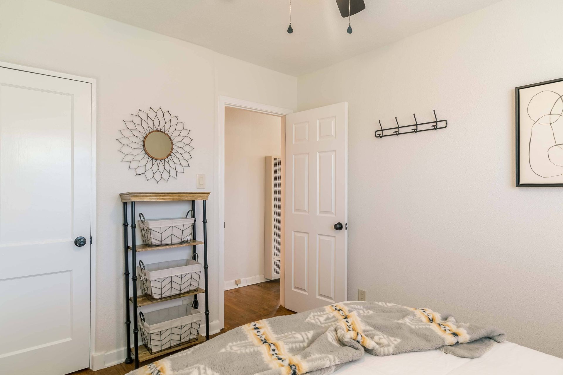 A bedroom with a bed , a shelf , a mirror and a ceiling fan.