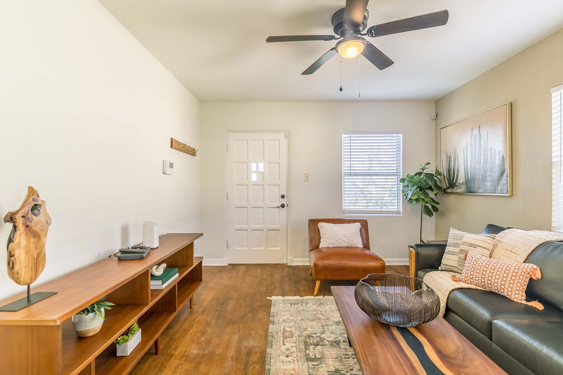 A living room with a couch , chair , coffee table and ceiling fan.