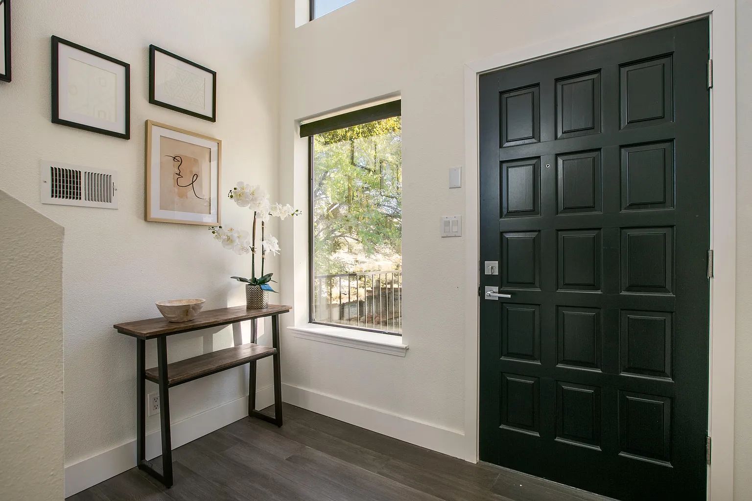 A hallway with a black door and a window.