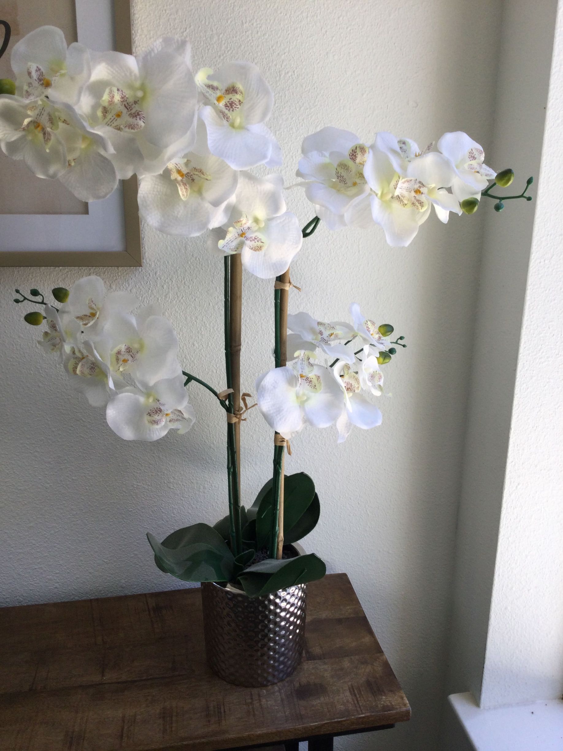 A vase filled with white flowers is sitting on a wooden table.