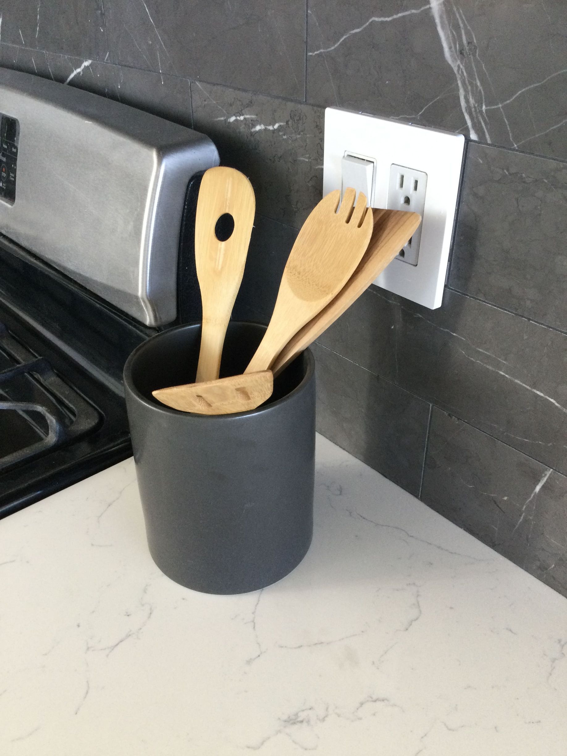 Wooden utensils in a black cup on a kitchen counter