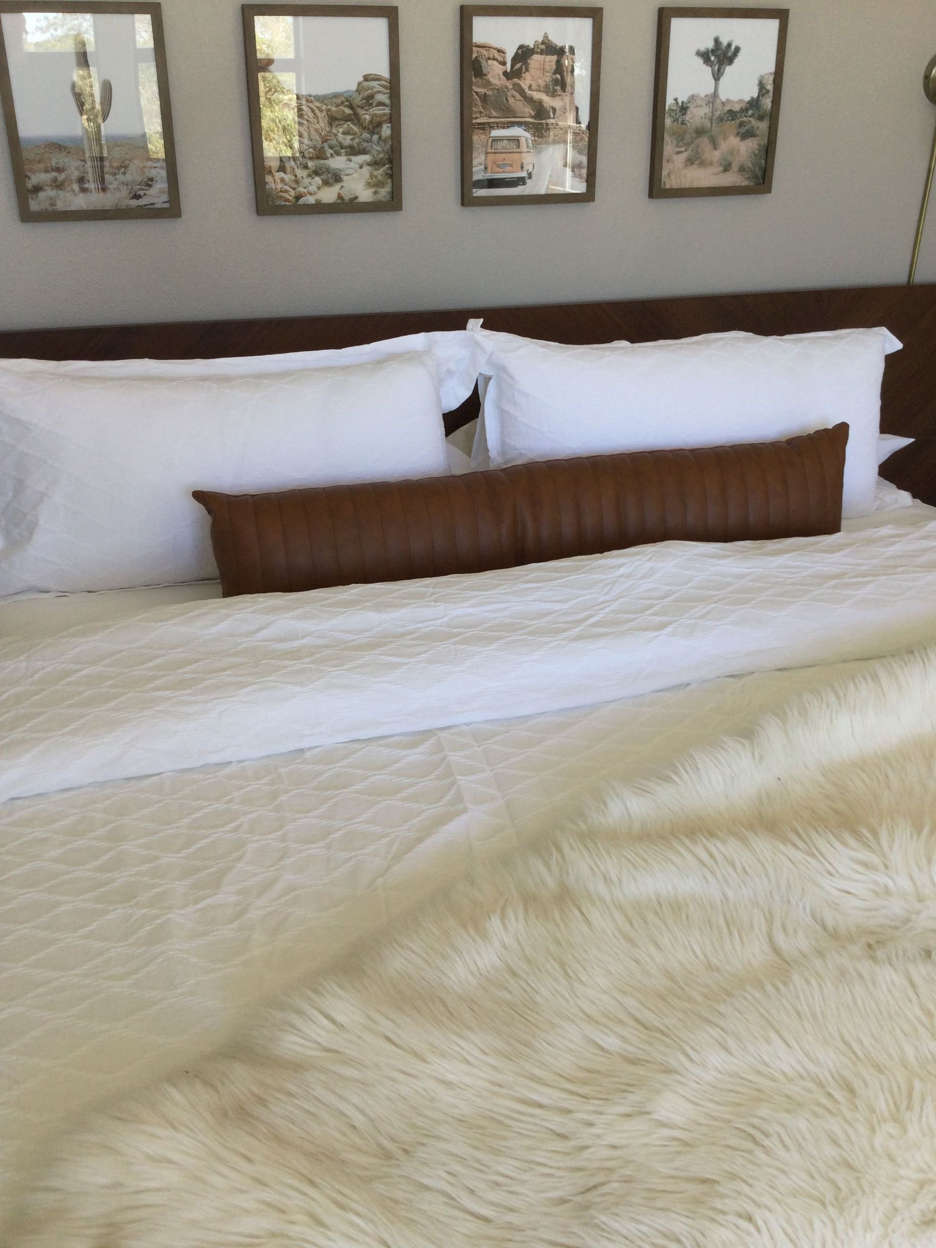 A bed with white sheets and brown pillows in a bedroom