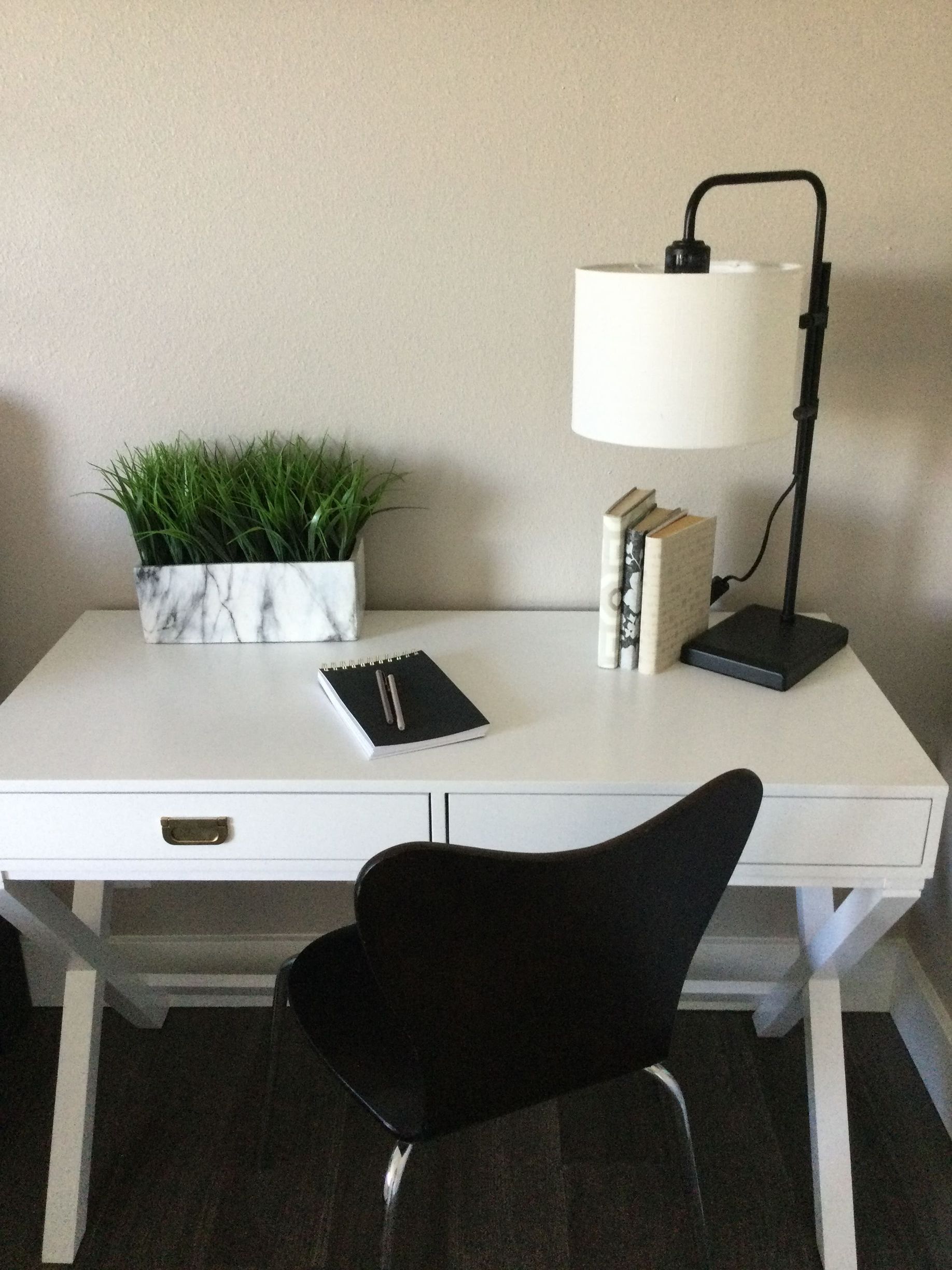 A white desk with a black chair and a lamp