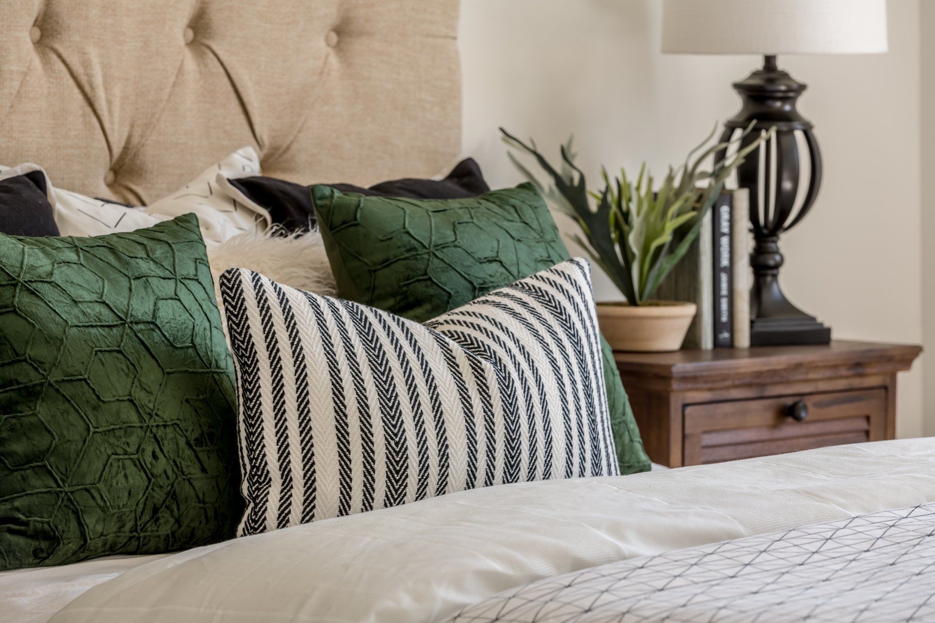 A bed with green and white pillows and a nightstand in a bedroom.