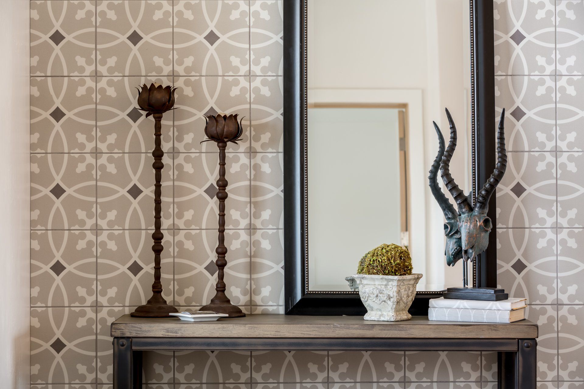 A table with candles , a mirror and a statue of an antelope on it.