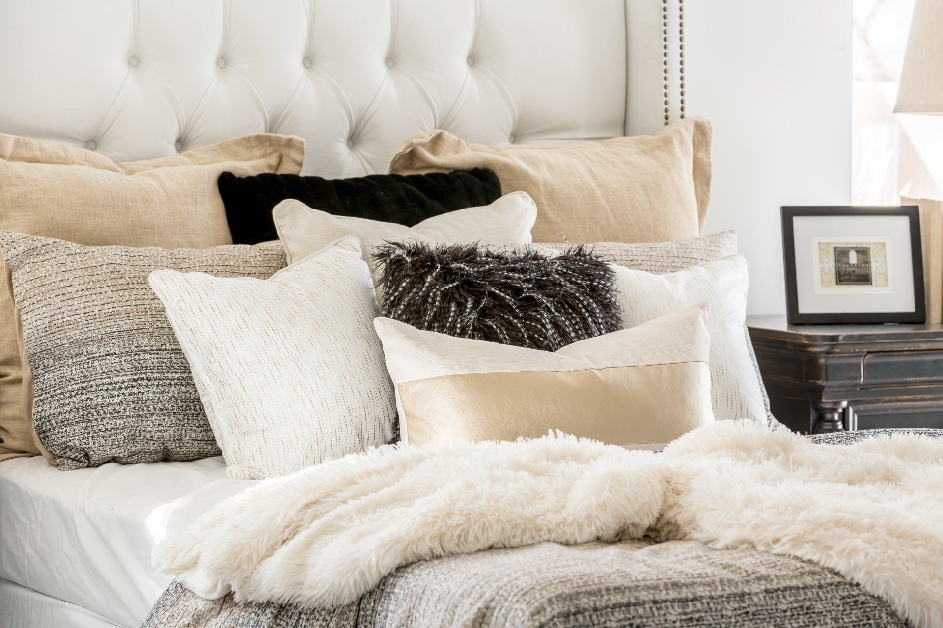 A bed with a white headboard and lots of pillows on it.