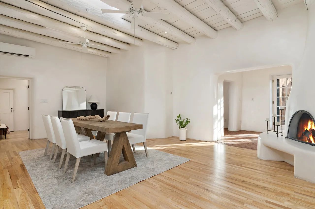 A dining room with a wooden table and chairs and a fireplace.