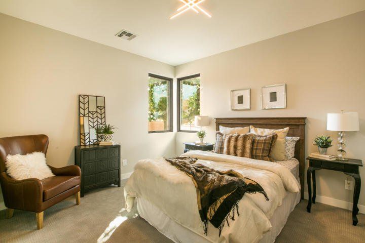 A bedroom with a bed , chair , nightstand and dresser.