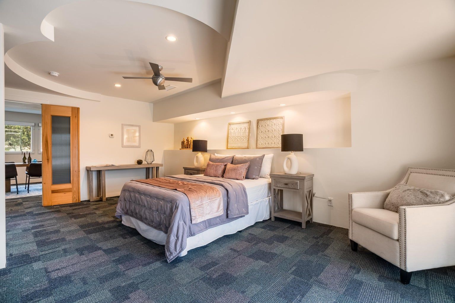A bedroom with a bed , chair , desk and ceiling fan.