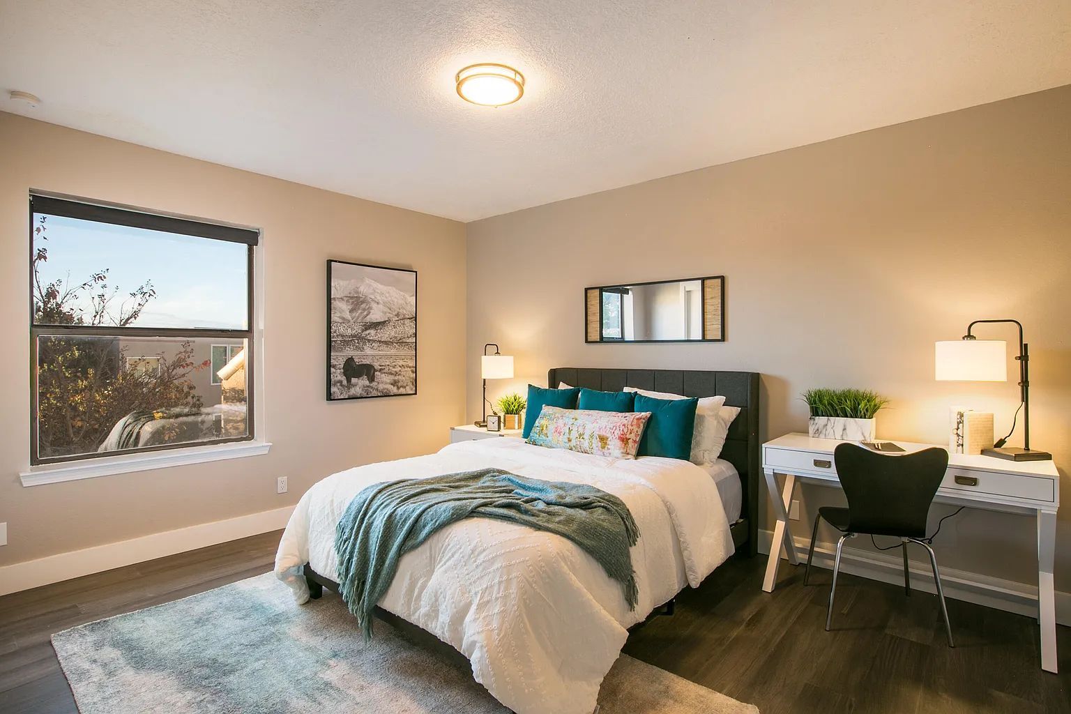 A bedroom with a bed , desk , chair and window.