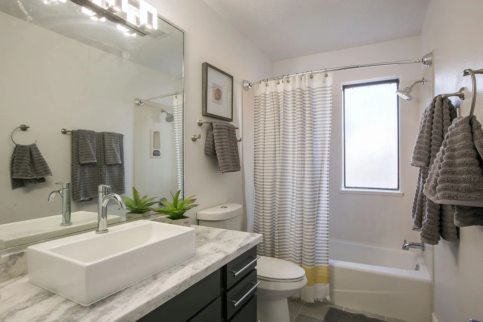 A bathroom with a sink , toilet , tub and mirror.