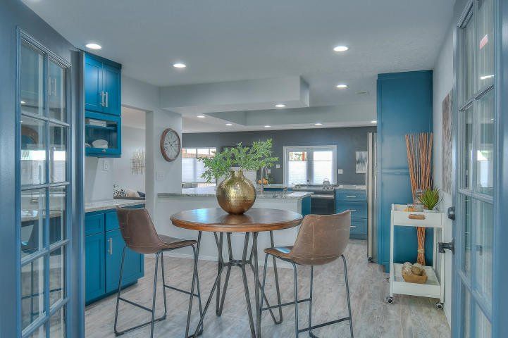 A kitchen with blue cabinets and a table and chairs in it.